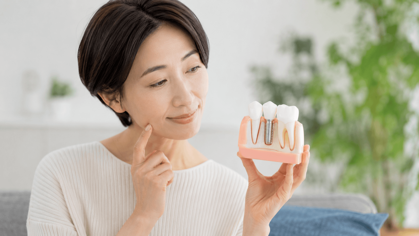 インプラントの模型を見ながら治療について考える女性