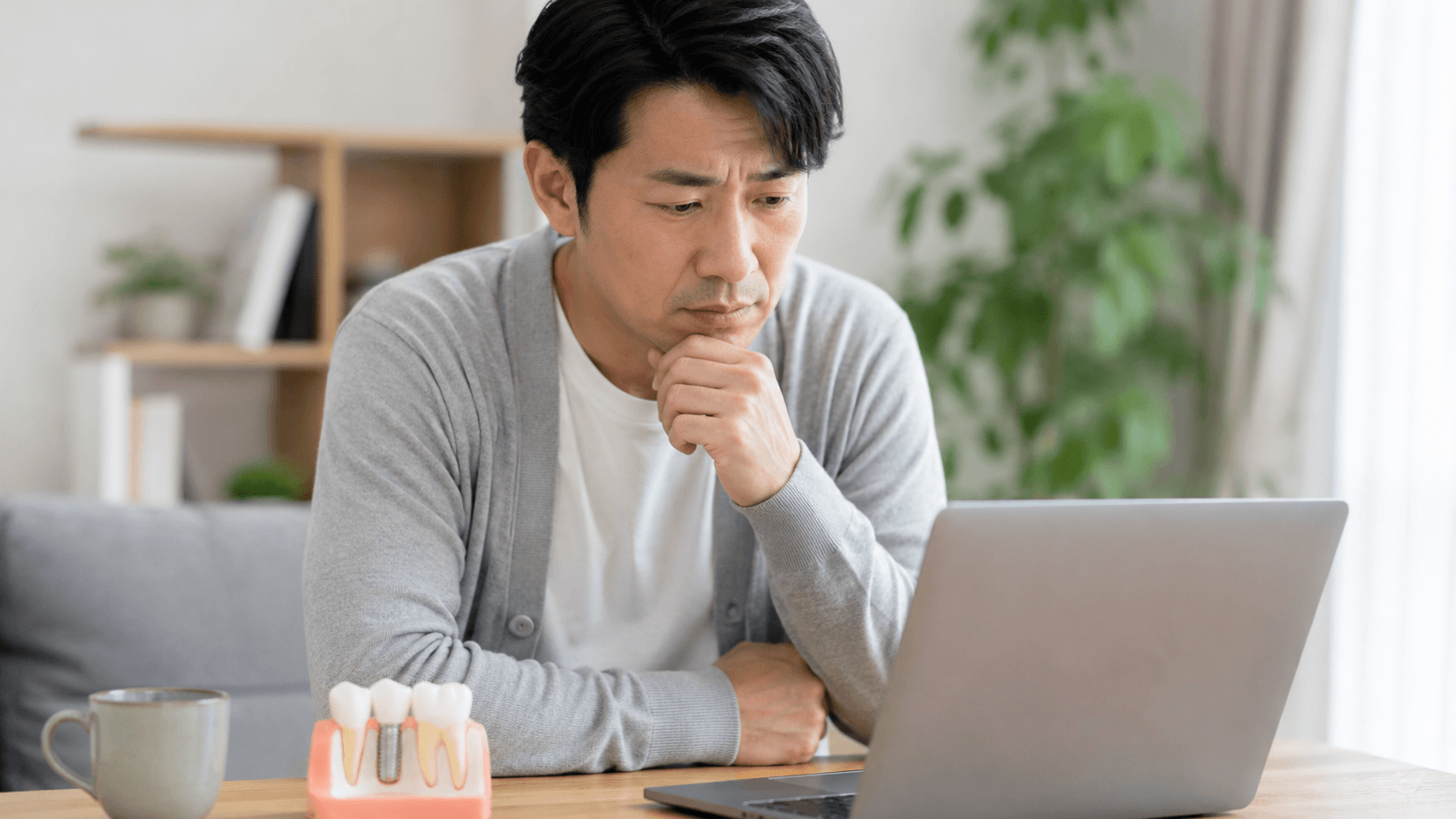 インプラントの費用や治療期間を調べる男性