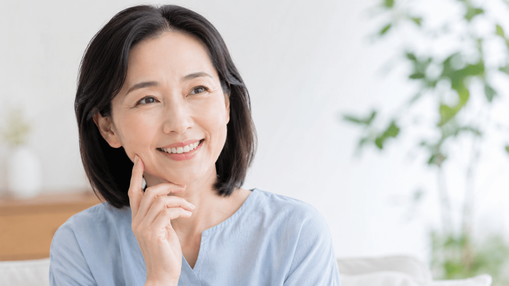 インプラント治療後の口元をイメージする女性